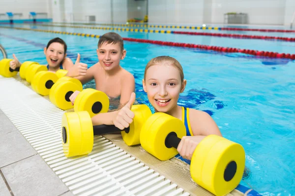 Grupo feliz e sorridente de crianças fazendo exercícios em uma piscina — Fotografia de Stock