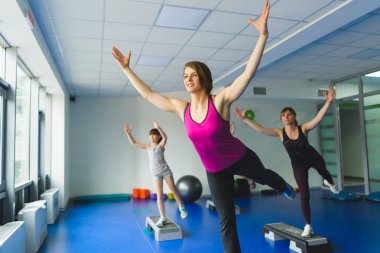 İki genç kadın ve küçük kızı jimnastik egzersizleri yapıyor