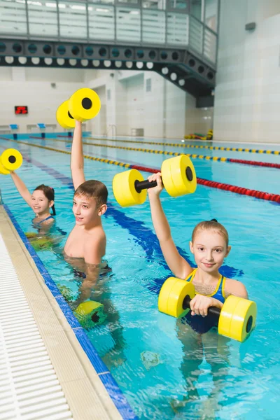 Fröhliche und lächelnde Gruppe von Kindern, die in einem Schwimmbad Übungen machen — Stockfoto