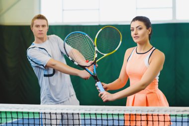 Mixed Doubles player hitting tennis ball, partner standing near net clipart