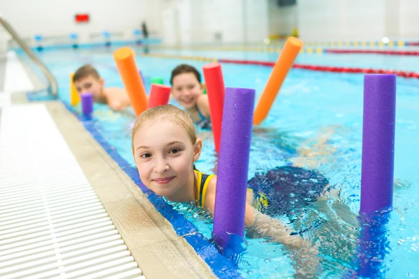 Szczęśliwa i uśmiechnięta Grupa dzieci nauki pływania z makaronem basen — Zdjęcie stockowe