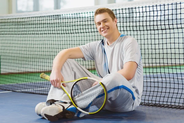 Young man smiling and posing with tennis racket indoor Royalty Free Stock Photos