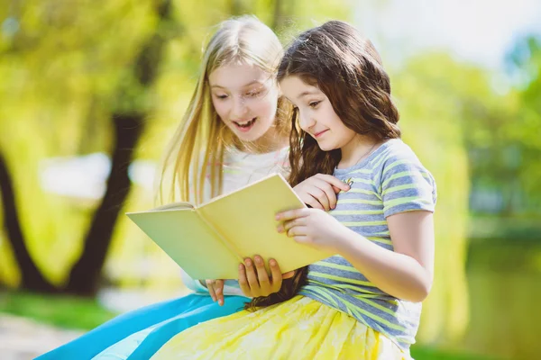 Діти читають книжки в парку. Дівчата сидять на деревах і озері на відкритому повітрі — стокове фото
