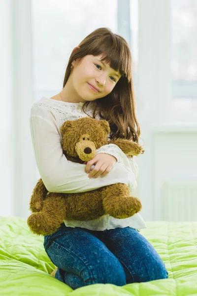 Felice gioiosa e sognante ragazza tenendo orsacchiotto al coperto — Foto Stock