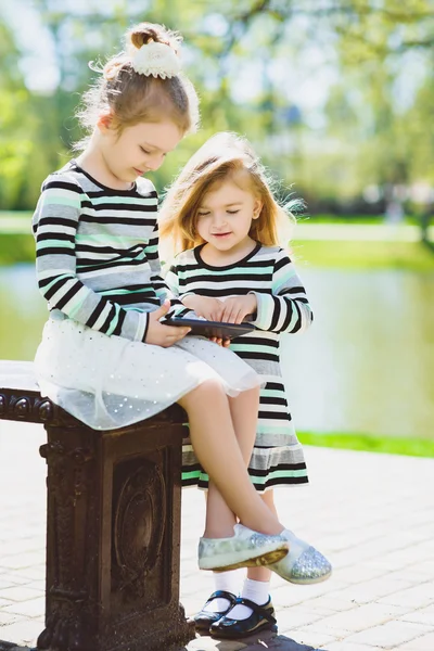 Due felici bionde bambine o sorelle che guardano tablet — Foto Stock