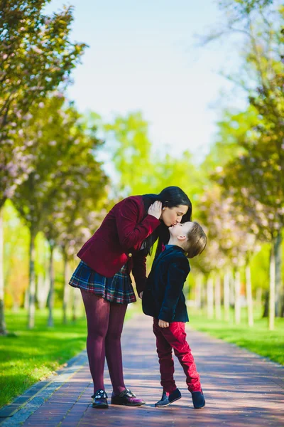 Ragazzo alla moda baciare la sua elegante madre all'aperto — Foto Stock