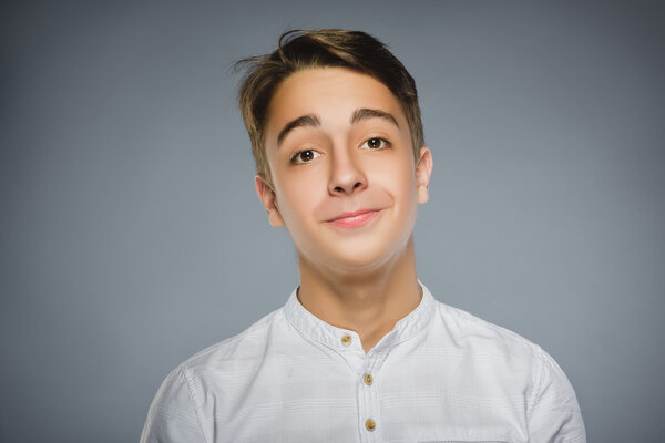 Happy boy. Closeup Portrait of handsome teenager in casual shirt smiling isolated on grey background