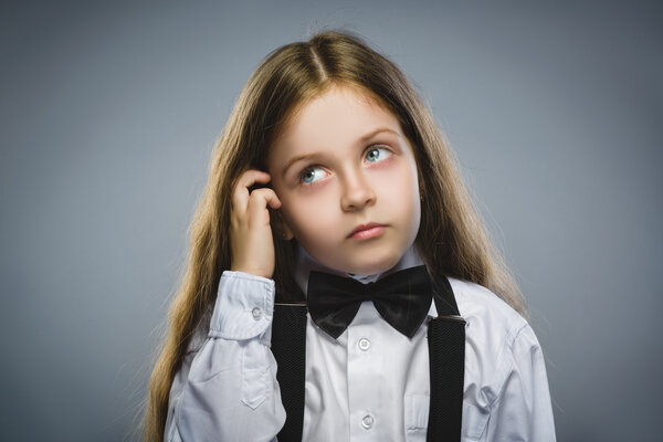Closeup Thoughtful Young girl Looking Up with Hand at Face isolated on Gray Background