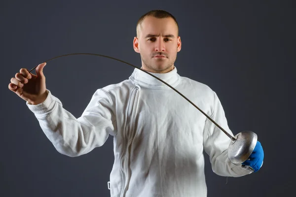 Esgrima atleta posando con una espada o epee sobre fondo gris — Foto de Stock