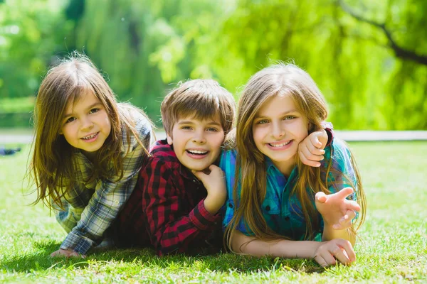 Niños sonrientes divirtiéndose en la hierba. Niños jugando al aire libre en verano. adolescentes comunicarse al aire libre — Foto de Stock