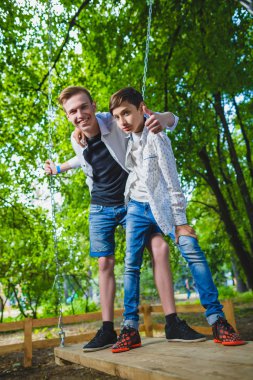 Gülümseyen çocuklar Bahçesi eğleniyor. Çocuklar açık havada yaz aylarında oynuyor. Gençler dışında bir salıncak üzerinde sürme