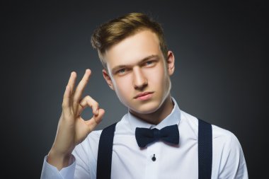 Mutlu çocuk. Yakışıklı genç gülümseyen ve gösteri Tamam bitti gri arka plan closeup portresi