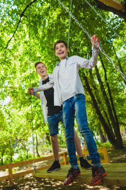 Gülümseyen çocuklar Bahçesi eğleniyor. Çocuklar açık havada yaz aylarında oynuyor. Gençler dışında bir salıncak üzerinde sürme