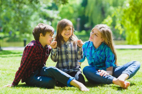 Bambini sorridenti che si divertono all'erba. Bambini che giocano all'aperto in estate. adolescenti comunicano all'aperto — Foto Stock