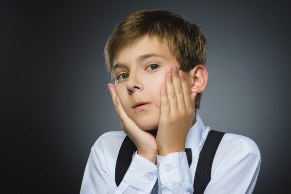 Крупный план Портрет красивого мальчика с изумленным выражением лица, стоящего на сером фоне
