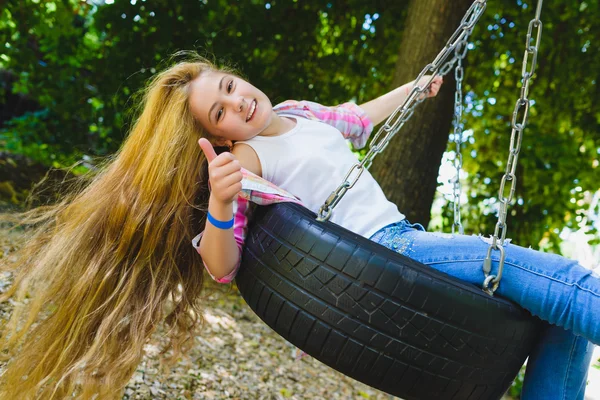 Una ragazzina al parco giochi. Bambino che gioca all'aperto in estate. Adolescente su un'altalena . — Foto Stock