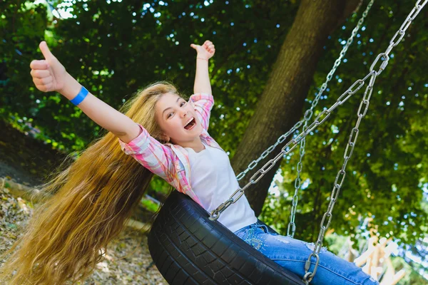 Una ragazzina al parco giochi. Bambino che gioca all'aperto in estate. Adolescente su un'altalena . — Foto Stock