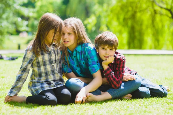 Bambini sorridenti che si divertono all'erba. Bambini che giocano all'aperto in estate. adolescenti comunicano all'aperto — Foto Stock