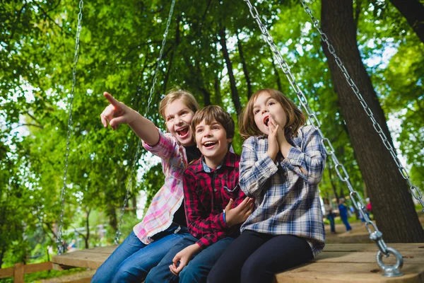 Senyum anak-anak bersenang-senang di taman bermain. Anak-anak bermain di luar ruangan di musim panas. Remaja naik di ayunan di luar — Stok Foto