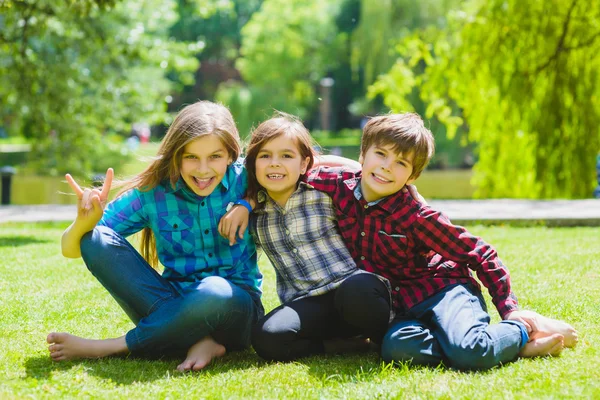 Bambini sorridenti che si divertono all'erba. Bambini che giocano all'aperto in estate. adolescenti comunicano all'aperto — Foto Stock
