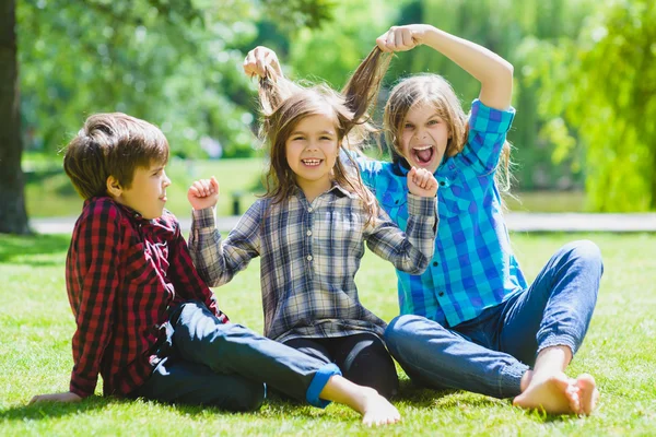 Bambini sorridenti che si divertono all'erba. Bambini che giocano all'aperto in estate. adolescenti comunicano all'aperto — Foto Stock