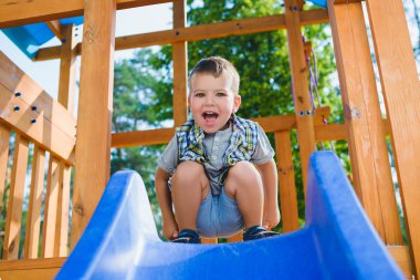 Gülümseyen çocuk parkında eğleniyor. Açık havada oynayan çocuk