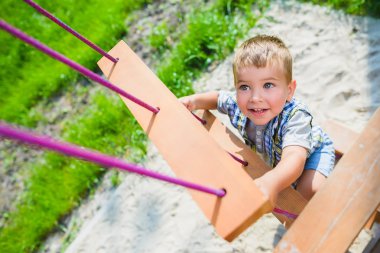 Gülümseyen çocuk parkında eğleniyor. Çocuk jimnastik egzersizleri yapıyor