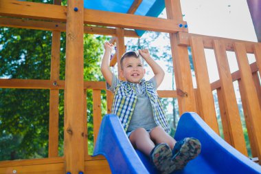 Gülümseyen çocuk parkında eğleniyor. Açık havada oynayan çocuk