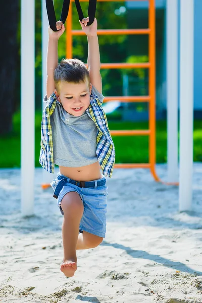 Χαμογελαστό παιδί που διασκεδάζουν στην παιδική χαρά. Το παιδί κάνει ασκήσεις γυμναστικής — Φωτογραφία Αρχείου