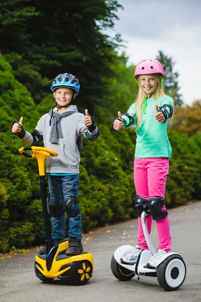 Niños felices de pie en el hoverboard o giroscooter al aire libre — Foto de Stock