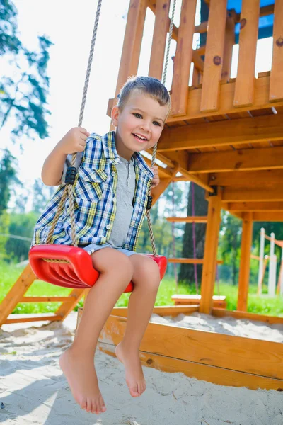 Anak laki-laki bersenang-senang atau naik pada ayunan di taman bermain luar — Stok Foto