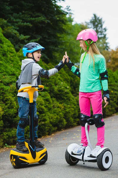 Niños felices de pie en el hoverboard o giroscooter al aire libre — Foto de Stock