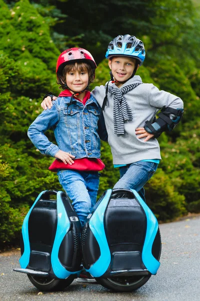 Niños felices de pie cerca de hoverboard mono-rueda o giroscooter al aire libre — Foto de Stock