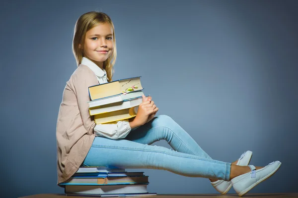 Iskola koncepciója. lány ül a könyvek és a gazdaság egy könyvet a kezében — Stock Fotó