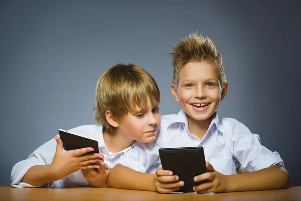 Koncepcja szkoły. Uśmiechający się zadowolony chłopców siedzi na biurko i Zachowaj ebooki — Zdjęcie stockowe