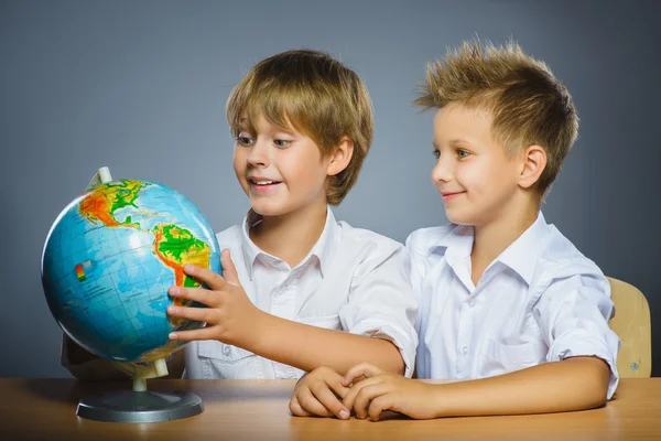 Concept van de school. Glimlachend gelukkige jongens zit aan Bureau en Toon op Globe — Stockfoto