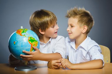 okul kavramı. Mutlu çocuklar masa başında oturan gülümsüyor ve dünya göster: