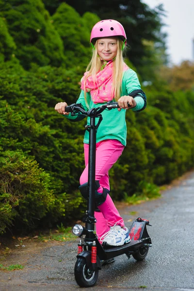 Chica feliz de pie en scooter eléctrico al aire libre — Foto de Stock
