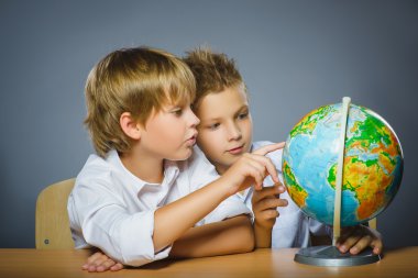 okul kavramı. Mutlu çocuklar masa başında oturan gülümsüyor ve dünya göster: