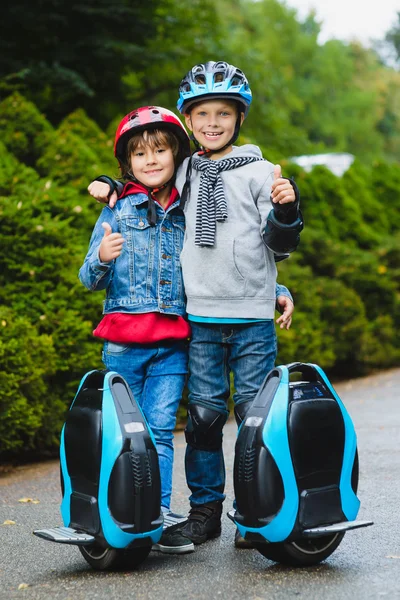 Niños felices de pie cerca de hoverboard mono-rueda o giroscooter al aire libre — Foto de Stock