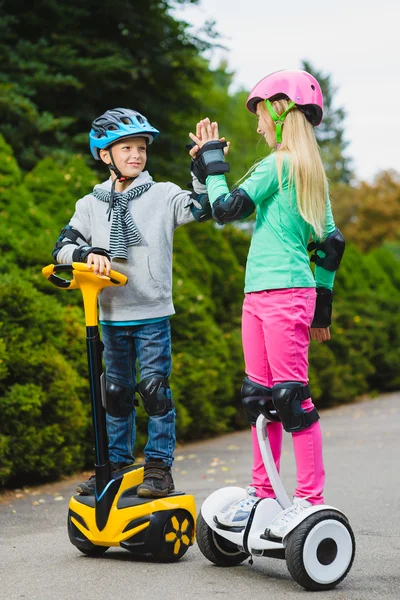 Niños felices de pie en el hoverboard o giroscooter al aire libre — Foto de Stock
