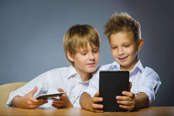 School concept. Smiling happy boys sitting at the desk and keep ebooks — Stock Photo, Image