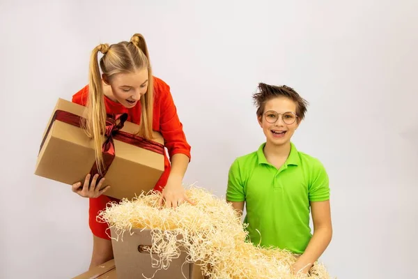 Dziewczyna i chłopiec przy kartonowych pudełkach przywiezionych z magazynu szukają prezentu — Zdjęcie stockowe