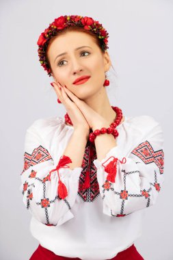 A beautiful, tall girl, in national Ukrainian clothes, with deep emotion and an exciting look, expresses sadness, love, close-up on a white background.