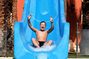 Boy in summer on vacation, has fun, on water slides