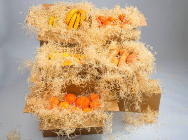 Meyve ve sebzelerle dolu karton kutular. Merdivenlerin yakınındaki beyaz arka planda talaş tozuyla kaplanmış.