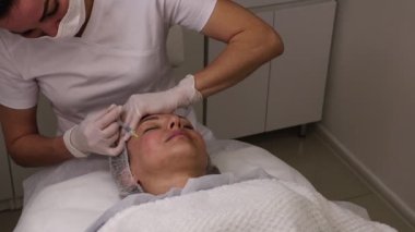 Biyolojik evrim, mezoterapi prosedürü, hiyalüronik asit enjeksiyonları, cilt gelişimi ve gençleştirme, yüz hatlarını düzeltme, güzellik uzmanı ve hasta, yakın çekim.