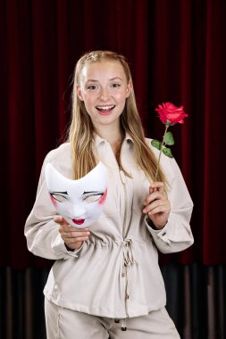 Gülümseyen güzel bir pandomimci kız elinde bir gül ve bir maske tutuyor. Yakın plan..