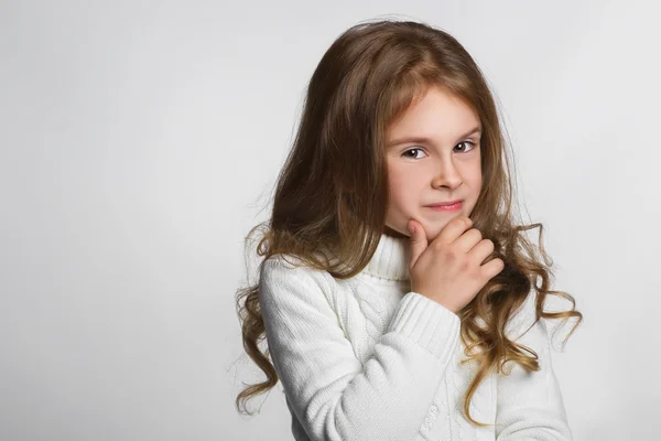 Porträt eines kleinen Mädchens, das über einem grauen Hintergrund denkt — Stockfoto