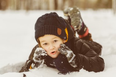 Küçük çocuk karda eğleniyor.